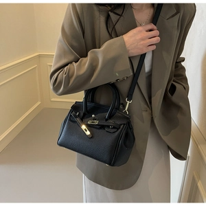 Detailed close-up of a black lychee texture leather handbag with elegant metal hardware