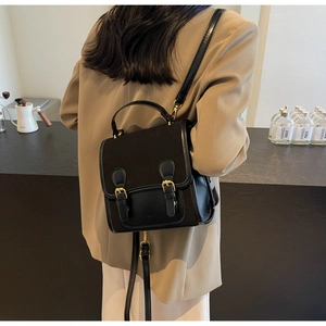 Close-up of vintage black school backpack with dual gold buckles and textured finish
