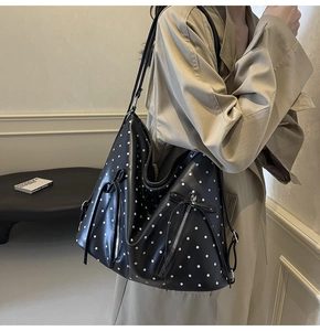 Close-up of black leather polka dot hobo bag with side zipper and elegant tassel detail