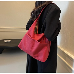 Close-up of red tote bag with lychee texture and dual front pockets on black coat