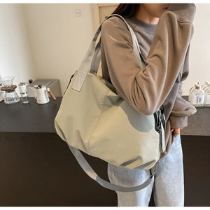Macro shot of large light green nylon tote bag showing spacious design and shoulder strap