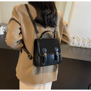 Rear view of model wearing a vintage black leather backpack with double buckle details