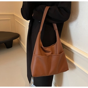 Detail view of large brown faux leather tote bag with functional front pockets