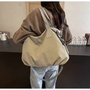 Rear view of a mint green pleated tote bag worn by a model in a minimalist store setting