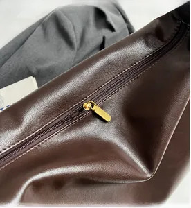 Gros plan d'une fermeture éclair dorée fluide sur un sac cabas vintage marron foncé