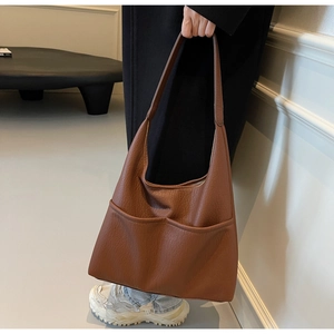 Close-up of brown tote bag with litchi grain texture and functional front pockets