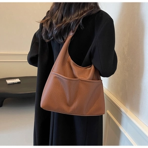 Brown lychee leather hobo bag with dual front pockets shown on model shoulder