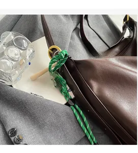 Détail du cabas en cuir mat marron foncé avec cordon tressé vert et breloque smiley jaune