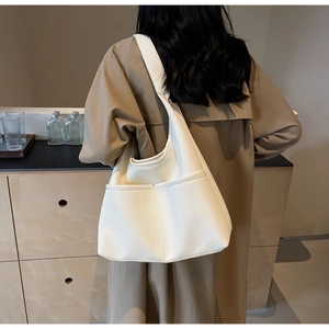Chic beige faux leather tote bag with exterior side pockets shown on female model