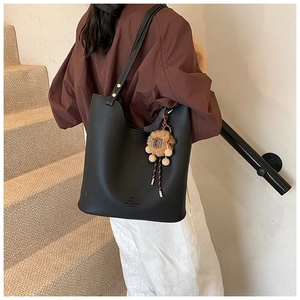 Close-up of black pebble leather tote bag with gold rivets and plush lion charm detail