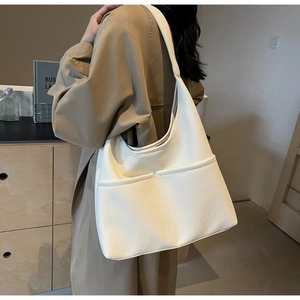 Detailed close-up of white pebble leather tote bag featuring dual front pockets and soft texture