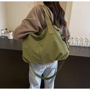 Olive green nylon tote bag shown in a lifestyle setting on woman's shoulder