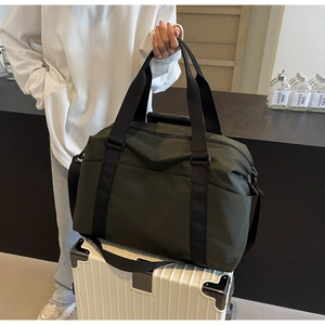Dark green travel bag placed on a suitcase, showing large capacity and shoulder strap
