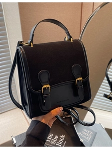 Classic black dual-buckle backpack in matte and smooth leather texture with gold hardware