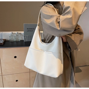 Detail view of cream white textured leather tote bag with two front pockets on shoulder