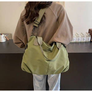 Detailed view of an olive green oversized tote bag with nylon straps and black metal hooks