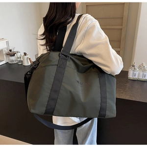 Olive green travel duffel bag shown on model in a modern cafe setting for daily use