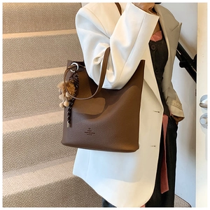 Detail of dark brown pebble leather tote bag with plush bear charm and Paris logo