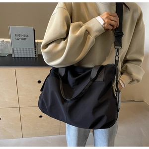 Detailed view of the large black travel tote with adjustable straps in a lifestyle setting