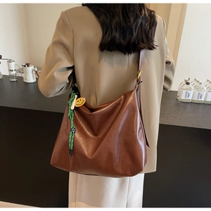 Détail du sac hobo souple en PU marron avec breloque smiley et bandoulière réglable