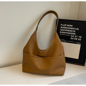 Macro shot of tan faux leather tote with litchi texture and front pocket detail