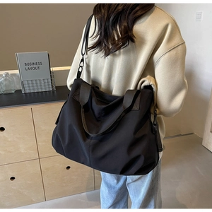Black large capacity nylon tote bag with wide shoulder strap shown in a back-view pose