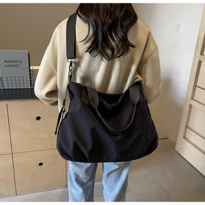 Detail showing back view of large black tote bag on model for scale and fit