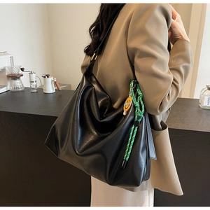 Détail du grand sac hobo noir avec nœud vert et étiquette smiley pour femme élégante