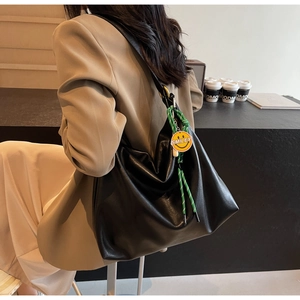 Détail d'un sac hobo en cuir noir avec un porte-clés smiley tressé et une texture souple