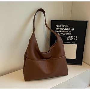 Detail of a brown lychee-grain leather tote bag with elegant decorative seam stitching