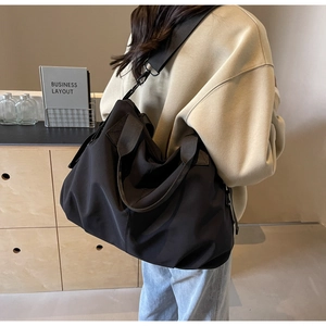 Rear view of a large black nylon tote bag on a model showing drape and capacity