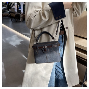 Detail of blue denim box bag with leather handles and jeans-inspired stitch design