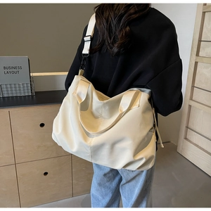 Lifestyle shot of large off-white tote bag with wide strap on woman shoulder