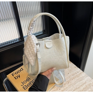 Detail of light beige bucket bag with woven handle and elegant checkered silk scarf accent