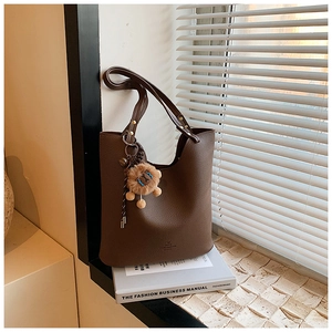 Detail view of retro brown textured leather tote with cute lion charm on a fashion book