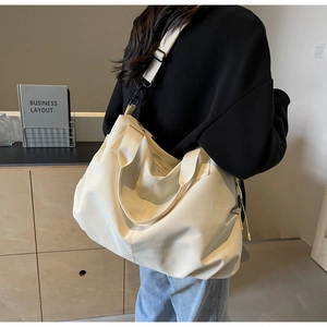 Detail of a large cream canvas tote bag with adjustable wide strap and metal buckle