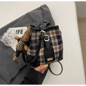 Detailopname van retro geruite emmertas met konijntjeshanger op een grijze blazer achtergrond