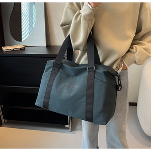 Detail of teal travel bag with reinforced handles and metal D-rings for shoulder straps