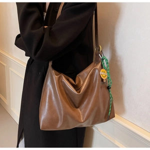 Détail d'un grand sac cabas marron en similicuir avec corde tressée et pendentif smiley