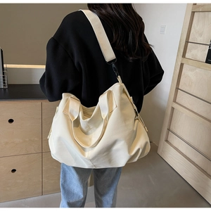Rear view of a model wearing the cream canvas tote bag with adjustable shoulder strap