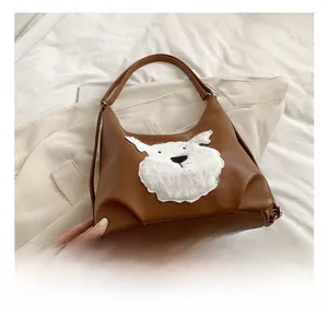 Close-up of brown leather bag featuring a white plush dog patch and smooth strap