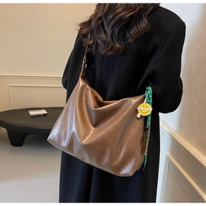 Détail d'un grand sac hobo marron avec breloque smiley jaune et large bandoulière