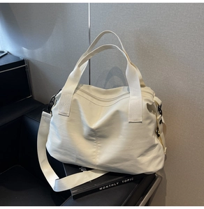 Close-up of cream large capacity travel bag with adjustable strap and smooth nylon fabric