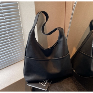 Detail of black pebbled leather tote bag featuring two front vertical slip pockets