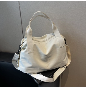 Detail of ivory nylon tote bag with wide adjustable shoulder strap and black metal zippers