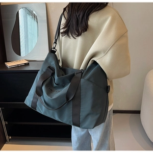 Deep green large travel bag shown in home setting with adjustable shoulder strap