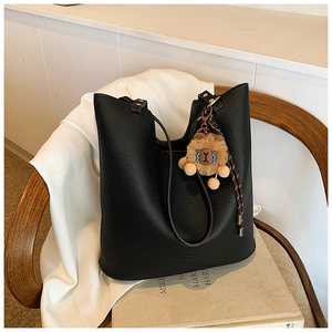 Close-up of black litchi pattern leather tote bag with a cute brown bear pendant