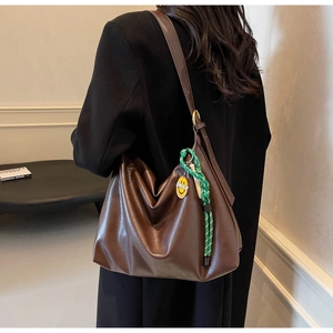 Gros plan sur un grand sac cabas marron au design plissé avec pendentif smiley