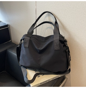 Detail of a black large capacity nylon tote bag with wide handles and shoulder strap