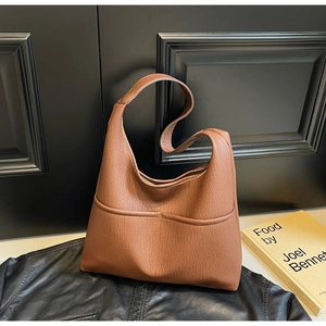 Close-up of brown litchi pattern leather tote bag with functional front pockets on black surface